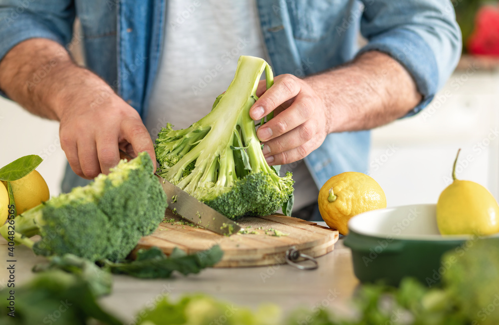 Man preparing delicious and healthy dinner of broccoli at home kitchen - obrazy, fototapety, plakaty 
