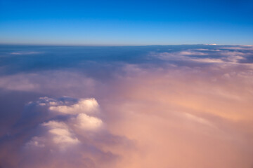 Wall Mural - view on the sky and clouds from the porthole of a plane at sunset