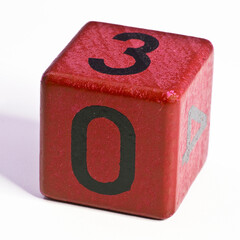 Number zero and three written on a red wooden cube of a calendar date