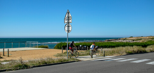 Vendée, France, January 2, 2021: From the Sauzaie spot, a couple on a bicycle ride on the cycle path along the ocean, Bretignolles Sur Mer.

