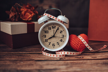 Alarm clock, heart shape and gift box on wood table. Love, gift, valentine concept.