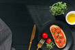 Tasty sandwich with cherry tomatoes, micro greens and avocado on wholegrain bread on black wooden background. Healthy delicious breakfast or lunch concept. Top view, copy space