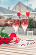 Pink champagne in two glasses, heart shaped french macaron and roses on a balcony table. Romantic, love or Valentine's day concept