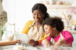 © Prostock-studio - Black mom and little daughter checking dough recipe online on digital tablet