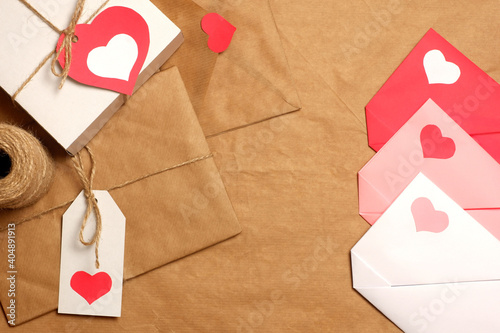 Gifts and envelopes, colored and wrapped in brown craft paper, tied with twine with bows and labels, hearts and coil of twine on craft paper background. Valentine's day romantic template 