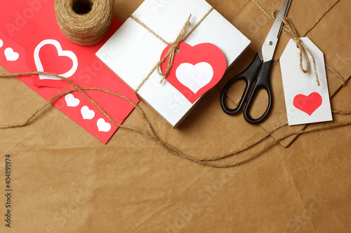 Gifts wrapped in brown craft paper, tied with twine with bows and labels, string, scissors, coil of twine on craft paper background. Love, Valentine's, mother's, women's day, romantic template 
