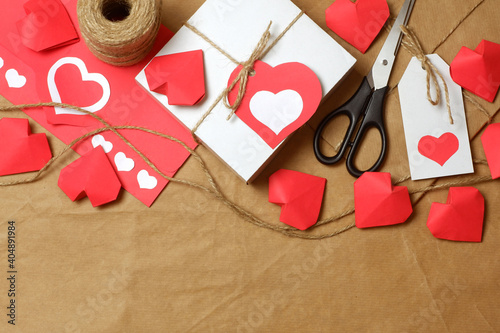 Gifts wrapped in brown craft paper, tied with twine with bows and labels, string, scissors, coil of twine, paper hearts on craft paper background. Love, Valentine's, women's day, romantic template 