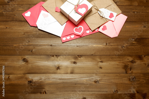 Love, Valentine's, women's day, relations, romantic composition from gifts and love letters, colored and wrapped in craft paper, tied with twine with bows and labels, hearts on wood background 
