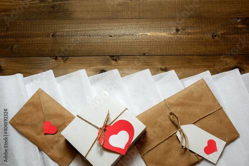 Valentine's day, love, romantic template from gifts and love letter with hearts, tied with twine with bows and labels on white crepe paper and wooden planks background 