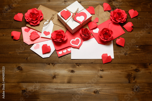 Love, Valentine's, women's day, relations, romantic design with gifts and envelope, wrapped in brown craft paper, tied with twine with bows, labels, handmade paper roses and hearts on wooden boards 