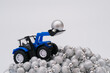 Blue tractor on pile of silver baubles. Winter holiday waste problem concept