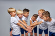 © Roman - friendly children soccer team getting ready to play, holding hands together, hoping to win, in uniform, isolated in studio