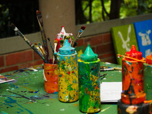 Close-up Of Paint Bottles And Brushes On Table