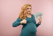 © rubchikova - A pregnant woman is counting money. Portrait of a pregnant woman in green dress  with us dollars