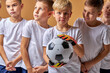 © Roman - boy goalkeeper holding soccer ball in hands and his friends near him, portrait