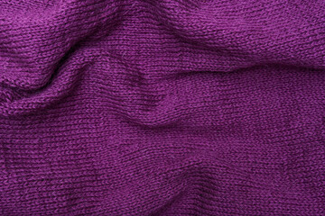 Woolen crumpled purple fabric as background close-up, violet knitted clothes, crochet and knitting