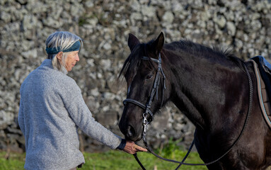 Woman riding a black Lusitano horse outdoors, good weather, Azores.