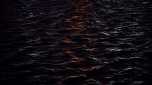 Wavy Ocean Surface In The Rays Of The Setting Sun. Dark Sea Water With Reflection Of Red Rays Of The Sun. Water Background