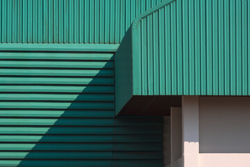 Wall Mural - Sunlight and shadow on part of green corrugated metal roof with louver on the wall of large factory building