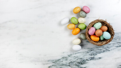 Sticker - Happy Easter concept with basket of colorful eggs and nest on stone background in flat lay format