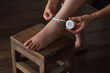 Woman measuring foot affected by lymphedema condition with tape measure