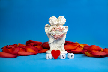 Two cute angels and the word love on the background of rose petals .Valentine's Day. Postcard for the holidays