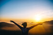 © Scopio - Silhouette of person raising their hands during sunset on mountain peek