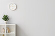 © Pixel-Shot - Rack with decor and houseplant against light wall with clock in room