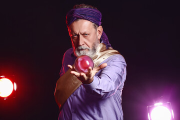 Wall Mural - Male fortune teller with crystal ball on dark background