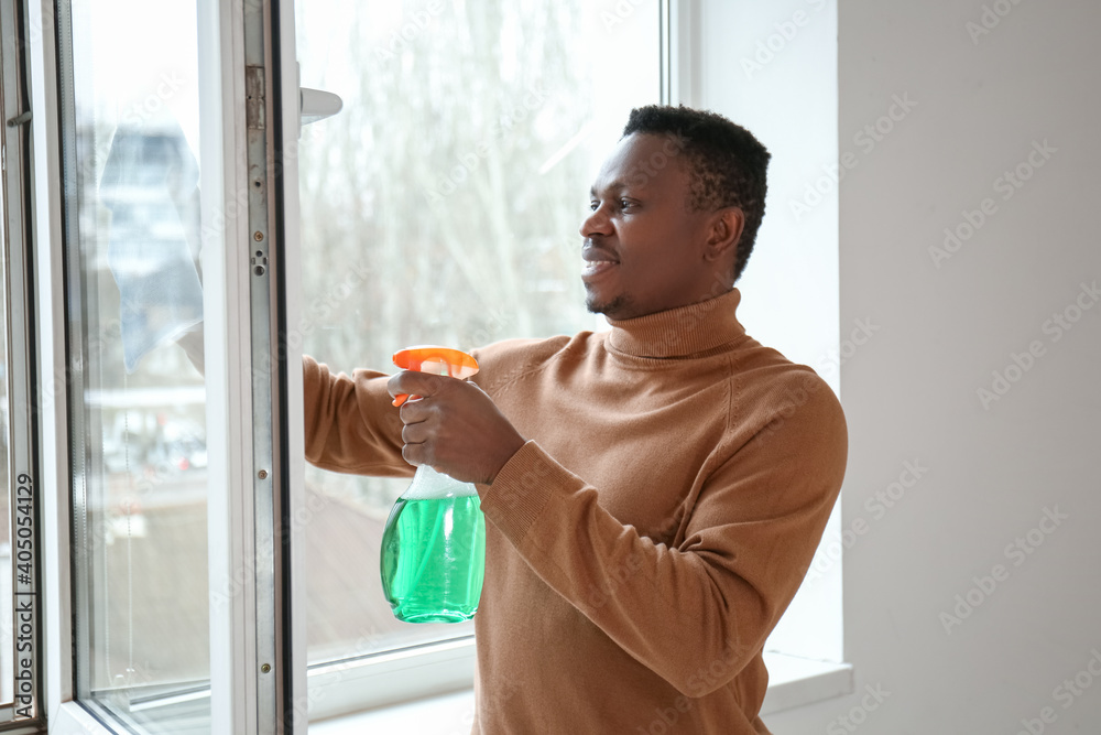 African-American man cleaning window in his flat