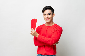 Wall Mural - Smiling handsome Asian man holding red envelopes or Ang Pao in studio isolated gray background for Chinese new year concepts