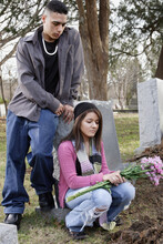 Young Hispanic Couple At Grave