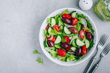 Wall Mural - Healthy green salad with fresh tomato, cucumber, red onion, olives and lettuce in bowl