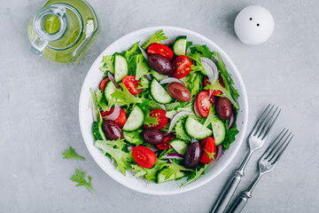 Wall Mural - Healthy green salad with fresh tomato, cucumber, red onion, olives and lettuce in bowl