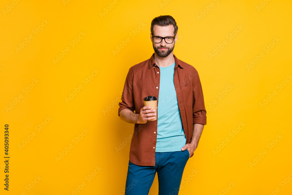Photo portrait of bearded man in glasses keeping cup with coffee in casual clothes isolated on vivid yellow color background - obrazy, fototapety, plakaty 