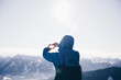 Wandernde Person bildet Rahmen mit Händen und genießt die Aussicht auf die schneebedeckten Berge an einem sonnigen Tag im Winter