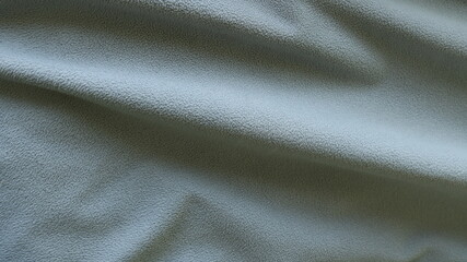 Wall Mural - large straight shaded folds on a textured sports material with a small rounded pile of a bluish-ash shade, a fabric gray background with embossed lines of volumetric space full frame