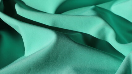 Wall Mural - a dense material of emerald luminous color, lying in meandering waves, brightly lit by sunlight and shaded in the curves, wavy pistachio green shining fabric with elegant folds