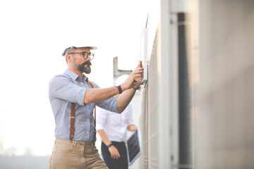 Portrait of Technician Electrical Engineer at rooftop building. Clean and green alternative energy concept.