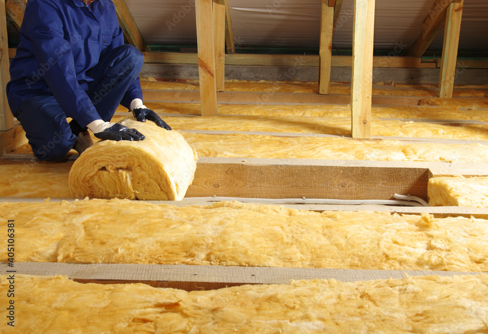 Worker thermally insulating house attic with glass wool - obrazy, fototapety, plakaty 