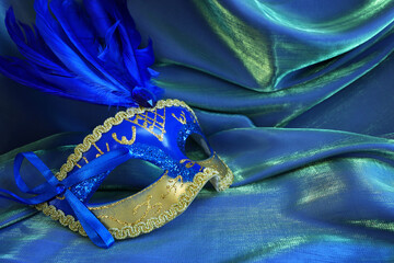 Photo of elegant and delicate Venetian mask over blue dark silk background