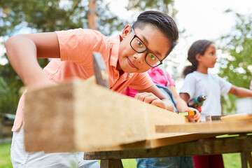 Boy at work with hammer and wood