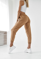 Canvas Print - fit woman standing in light beige pants and white shirt