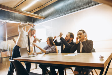 Keep calm. Angry boss with megaphone screaming at employees in office, scared and annoyed colleagues listening at the table stressed out. Funny meeting, business, office concept. Screaming mad.