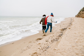 Wall Mural - Attractive young multiethnic couple walking at the beachside