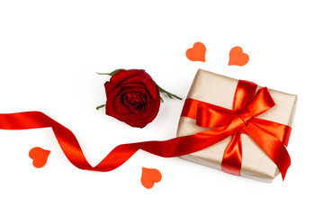 Gift box with red ribbon, little red heart and red rose on white background. Holidays and Valentin’s day romantic flat lay.