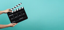 Hand Is Holding Black Clapper Board Or Clapperboard Or Movie Slate On Mint Green Or Turquoise Background.