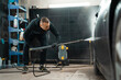 © Andrii  - Professional car wash. Detailing employee washes car with pressure washer