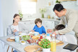 © Friends Stock - Caring latin father serving his adorable kids while having breakfast together at home