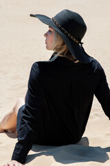 girl on a sand dune in a black hat and a beautiful forest view